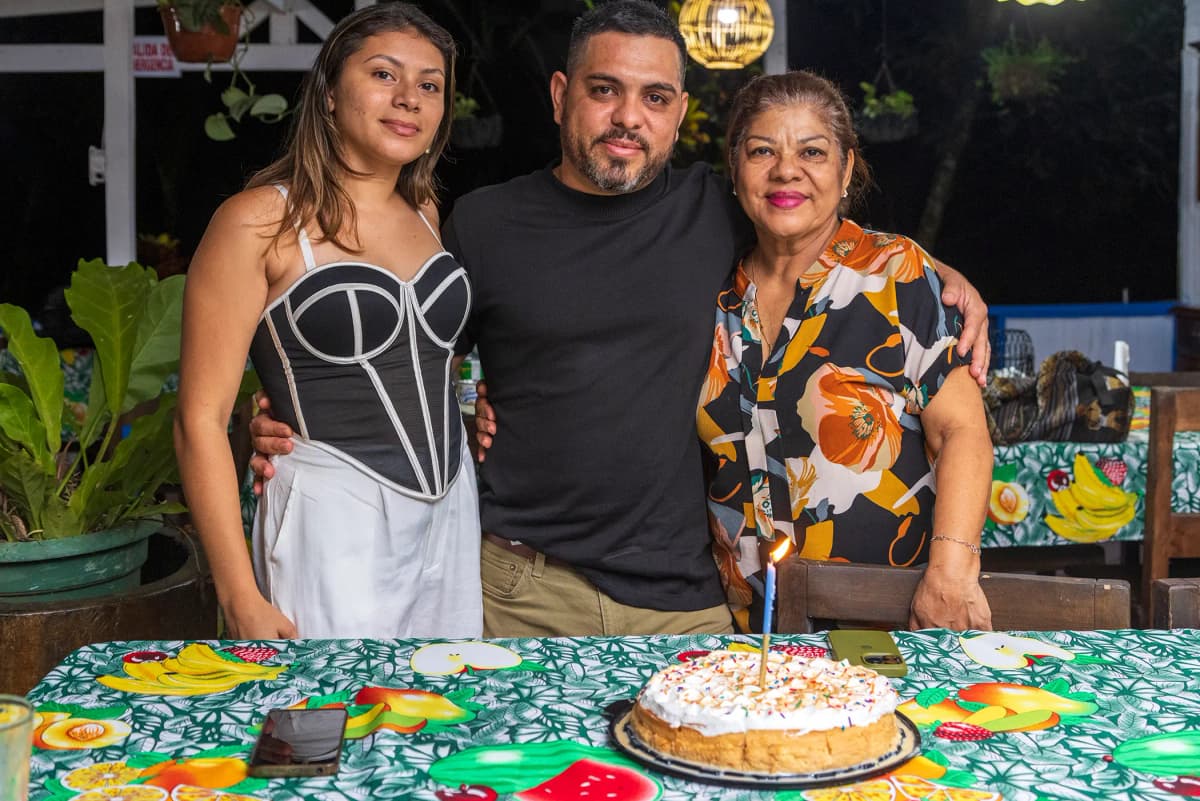 Retrato familiar de visitantes sonriendo junto a su pastel de cumpleaños