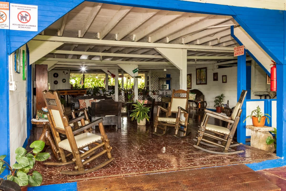 Entrada de la casona con mecedoras antiguas de madera y marcos azules