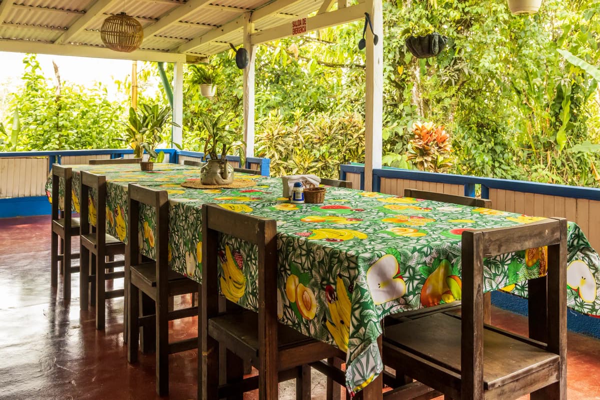 Mesa larga de madera con mantel de frutas en la terraza del restaurante