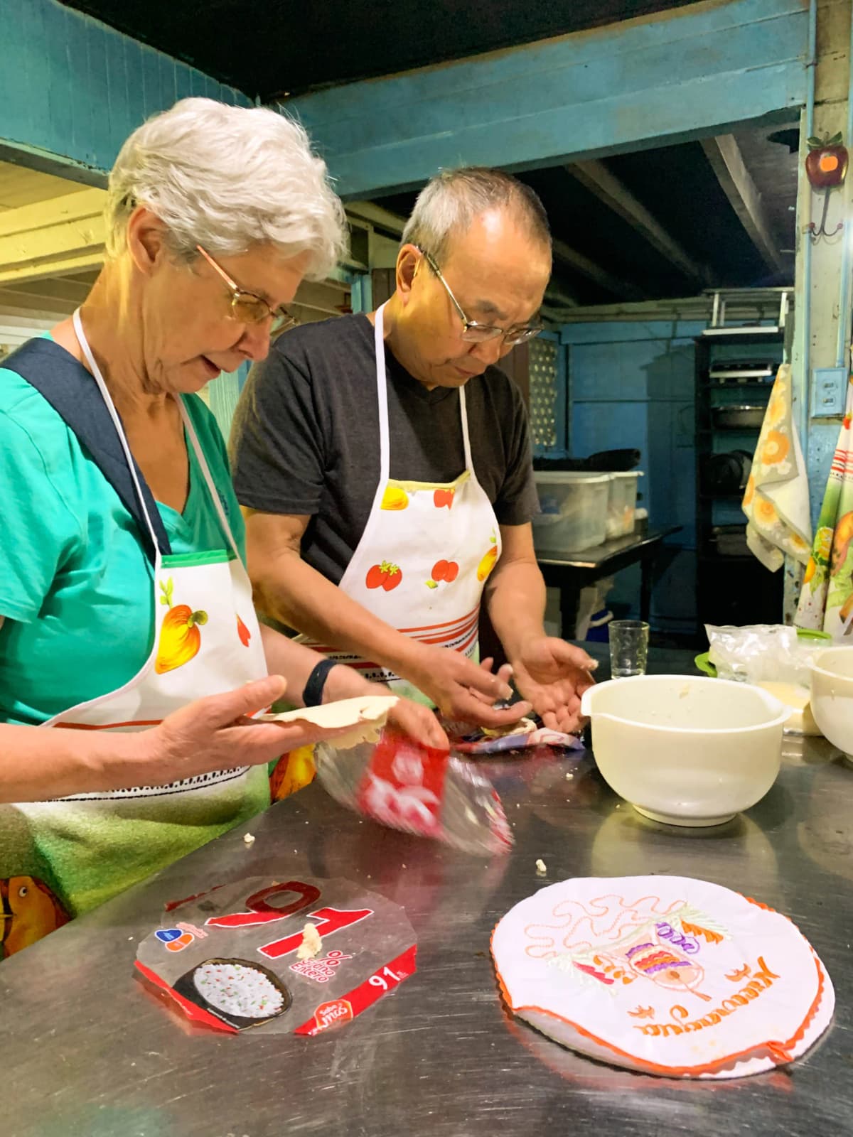 Pareja de adultos mayores elaborando tortillas de maíz artesanales en la clase de cocina