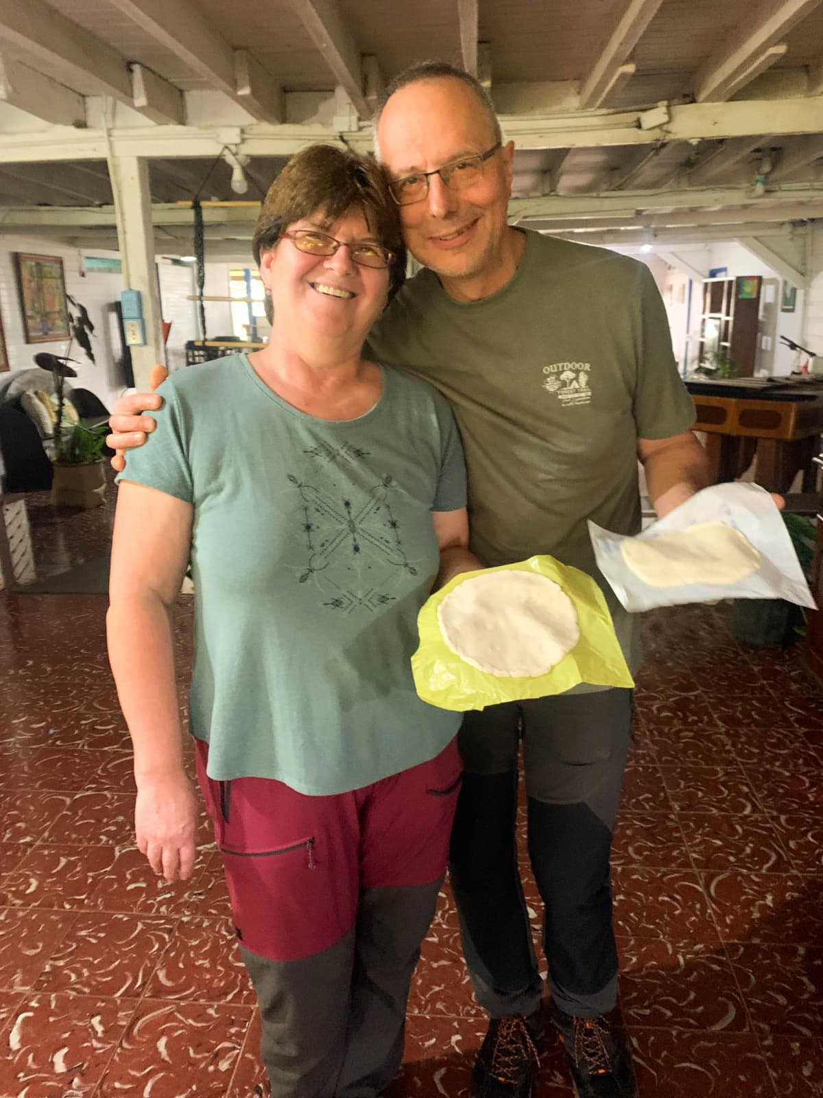 Pareja de turistas sonriendo y mostrando sus tortillas palmeadas hechas a mano