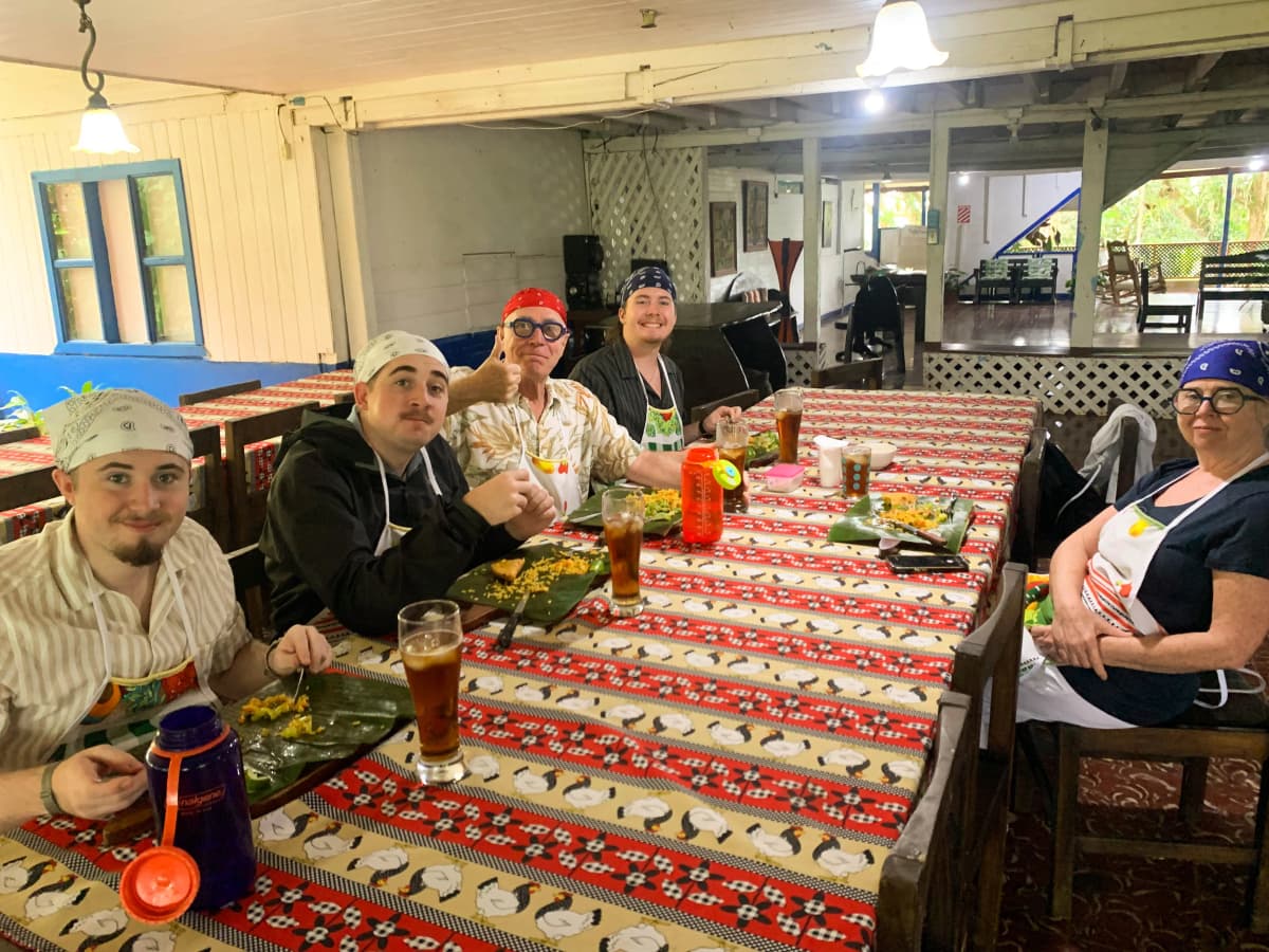 Grupo de visitantes sentados a la mesa disfrutando la comida preparada en la clase