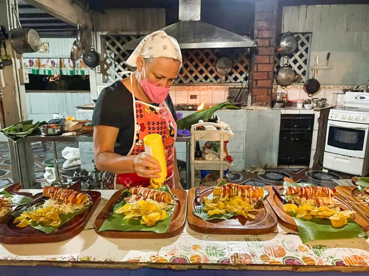 Tía Yami agregando salsas a platos de tacos ticos tradicionales servidos en tablas de madera