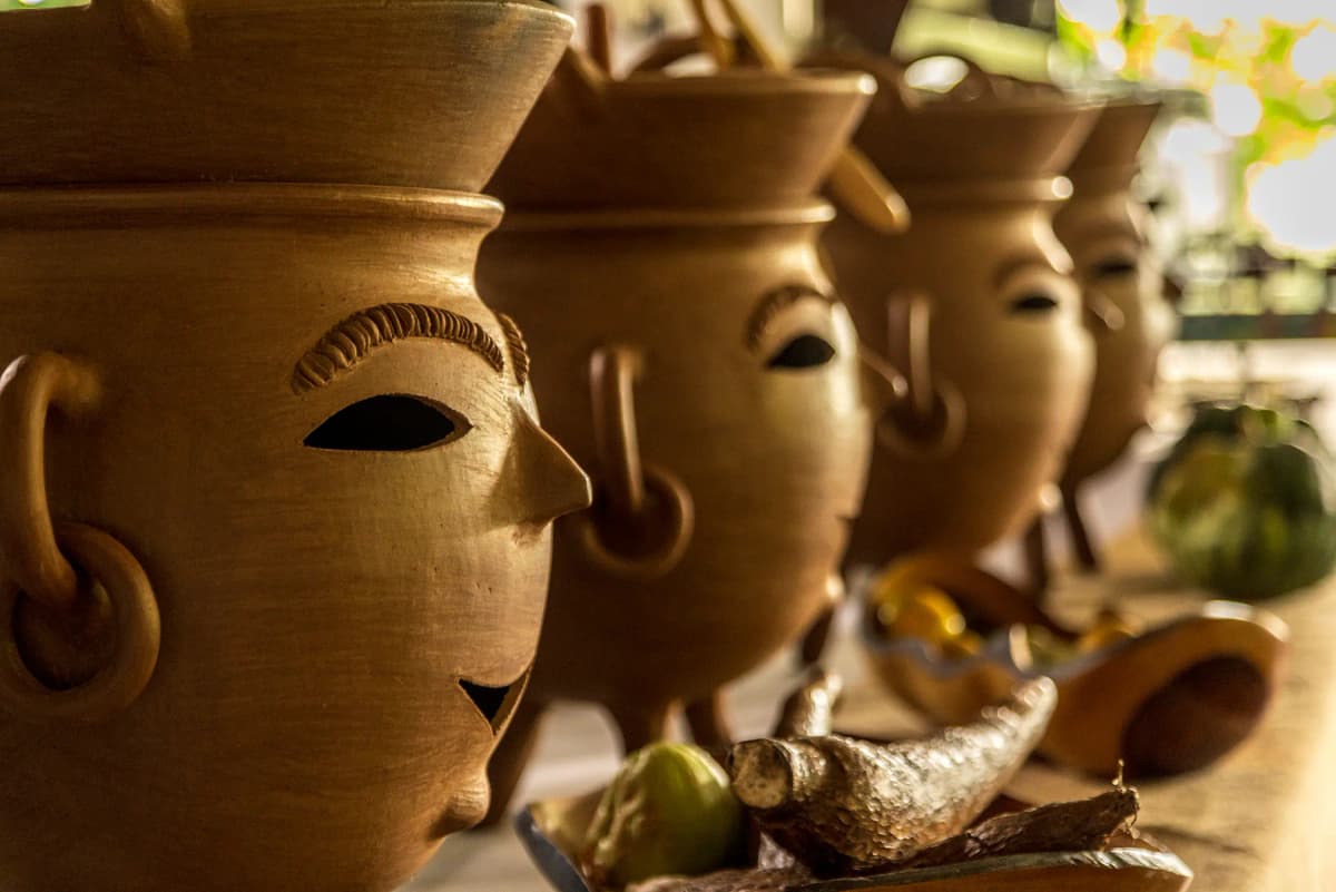 Primer plano de cazuelas artesanales esculpidas con rostros tradicionales