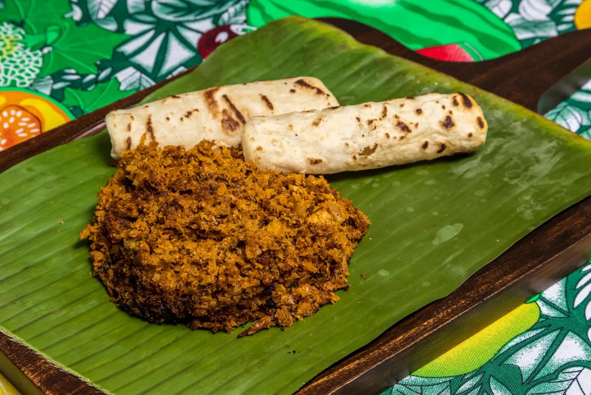 Picadillo tradicional costarricense servido sobre hoja de plátano con tortillas caseras