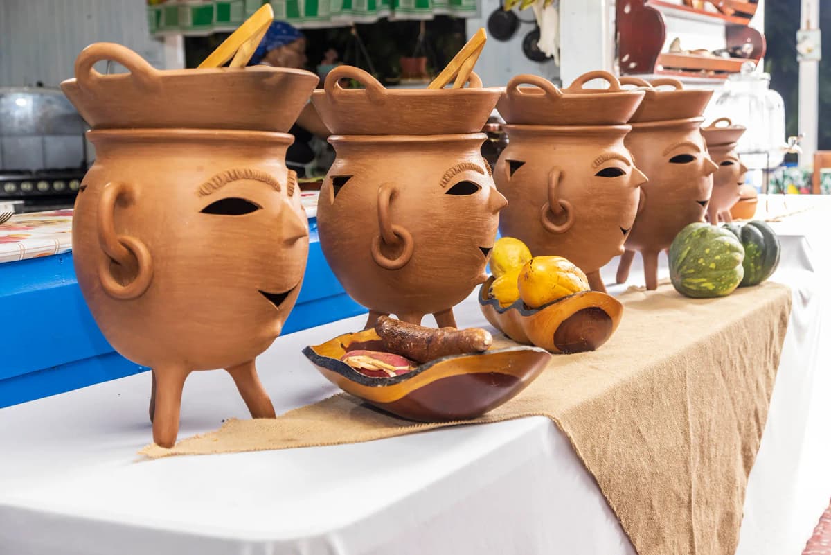 Cazuelas artesanales con rostros tallados en la mesa de servicio rústico